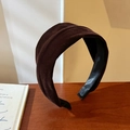 Primer plano de una diadema ancha de terciopelo marrón oscuro sobre base de madera - Marrón