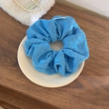Détail d'un chouchou en tricot bleu ciel avec motif ajouré sur un plateau en céramique - Grand / Bleu