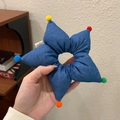 Dettaglio ravvicinato dell'elastico a stella blu con pompon colorati e etichetta logo - Blu