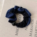 Detalle de coletero azul oscuro con costuras blancas y gran decoración de perla negra - Borde Azul Marino