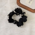 Dettaglio dell'elastico scrunchie leopardato con perla sintetica su sfondo di tessuto - Motivo Maculato Fondo Nero (Stile A)
