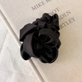 Détail d'un chouchou en satin noir avec fleur rose 3D sur un livre texturé - Noir