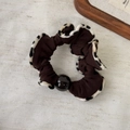 Dettaglio dell'elastico leopardato con una perla marrone lucida su sfondo in tessuto - Leopardo Caffè Scuro (Stile B)