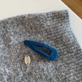 Nahaufnahme der dunkelblauen Filz-Haarspange mit silbernem ORO-Logo auf Strickgrund - Blau Wassertropfen