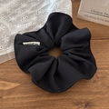 Detalle de un coletero negro con etiqueta de marca sobre una mesa de madera vintage - Negro