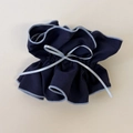 Détail d'un chouchou bleu marine à volants avec un nœud en ruban bleu clair brodé - Style Cintré Bleu