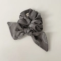 Dettaglio di uno scrunchie grigio con stampa paisley, fiocco a orecchie di coniglio e stile boho - Stile Fiocco Grigio