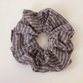 Dettaglio di un elastico per capelli a scacchi blu e marroni con etichetta del marchio - Scrunchie Grigio