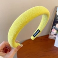 Detalle de una diadema acolchada amarillo brillante con etiqueta artesanal y punto fino - Amarillo