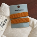 Detail of two ginger orange twill fabric BB hair clips on a display card stand - Orange Pair