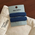 Detail of dark blue twill fabric hair clips in a 2-piece set on a brand display card - Light Blue Pair