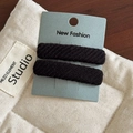 Detailed macro view of black twill fabric hair clips displayed on a branded card - Black Pair