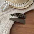 Dettaglio di fermagli per capelli leopardati e verde oliva su sfondo in maglia - Coppia Caffè Chiaro