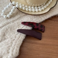 Dettaglio di fermagli per capelli maculati e in pelle viola su maglione a maglia - Coppia Rossa