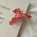 Gros plan d'une pince à cheveux en acétate à carreaux rouges et blancs sur un livre - Cintre Style