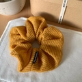 Detalle de coletero de malla tejida amarilla con etiqueta Fashion sobre lino - Naranja