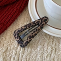 Detailaufnahme einer Haarspange mit Leopardenmuster auf weichem Strickhintergrund - Dreieck Kaffee Leopardenmuster