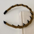 Diadema ondulada de pana marrón con tachuelas punk negras sobre un libro vintage - Verde amarillento