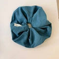 Close-up of blue corduroy hair scrunchie with hand-made label on a white surface - Blue