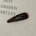 Dettaglio molletta per capelli leopardata su sfondo di tessuto beige rustico - Stile Goccia d'Acqua Cava