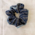 Close-up of blue plaid scrunchie fabric with contrast stitching on linen background - Blue Scrunchie
