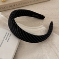 Close-up of black striped fabric headband with gold logo on soft knitted background - Black Wide Headband