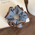 Blue striped scrunchie with brown faux fur trim and small brand tag on neutral fabric - Blue
