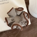 Nahaufnahme eines braun gestreiften Haargummis mit Plüschrand auf minimalistischem Buch - Kaffeebraun