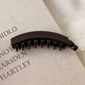 Close-up of a glossy dark brown acetate banana hair clip with secure inner teeth - Chocolate Brown