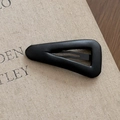 Detailed close-up of a minimalist black leather triangle hair clip on textured background - Triangle Style Black
