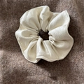 Premium cream white leather scrunchie with soft lychee texture on dark wool background - Off-white