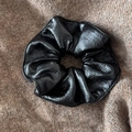 Close-up of black PU leather scrunchie with pleated texture on knitted fabric - Black
