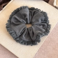 Oversized dark grey knitted scrunchie with fringe edges and Fashion label on book background - Gray