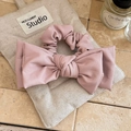 Dettaglio dell'elastico per capelli con fiocco in ecopelle rosa su sfondo di lino - Rosa