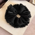 Detailed macro shot of a black knitted scrunchie featuring fringe edges and Fashion label - Black