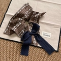 Nahaufnahme des Vintage-Haargummis mit braunem Blumenmuster und marineblauer Schleife - Großer Schleifen-Schal-Haargummi
