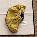 Detail of yellow polka dot fabric scrunchie combined with a glossy black claw hair clip - Skirt Edge Ponytail Clip