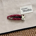 Détail d'une pince à cheveux à carreaux rouges avec un ours cartoon et logo Tagi - Barrette Chien en Tissu à Carreaux (Tagi)