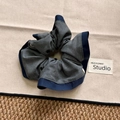 Dettaglio di elastico per capelli in tessuto grigio con bordino blu e pieghe morbide - Scrunchie di Base
