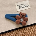Detailed close-up of a brown plush bear and flower hair clip on a beige canvas surface - Solid Blue Bear BB Clip