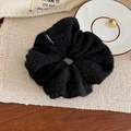 Detailed view of a fuzzy black wool scrunchie featuring a white Handmade fabric label - Black