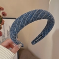 Detail eines dunkelblauen Twill-Haarreifens mit handgefertigtem Etikett und Stoffstruktur - Blau