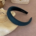 Close-up of handmade dark green sponge headband with soft velvet texture on fabric - Blue