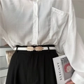 Dettaglio di una sottile cintura bianca con fibbia a foglia dorata su camicia e pantaloni - Bianco