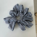 Dettaglio dell'elastico scrunchie a quadretti bianchi e neri con bordi blu e trama a pieghe - Quadri Blu
