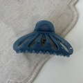 Detail view of a navy blue fan-shaped hollow hair claw on beige linen fabric - Dark Blue