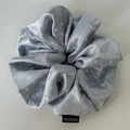 Detail showing light blue polka dot satin scrunchie with soft silk texture and fashion label - Blue