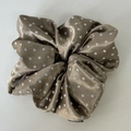 Close-up of champagne satin scrunchie with white polka dots and fashion label - Brown