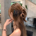 Set of two elegant black and white checkered hair clips worn by a model in a side view - Black