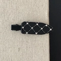 Detail van elegante zwarte gewatteerde haarclip met strass-steentjes en ruitpatroon stiksel - Zwart